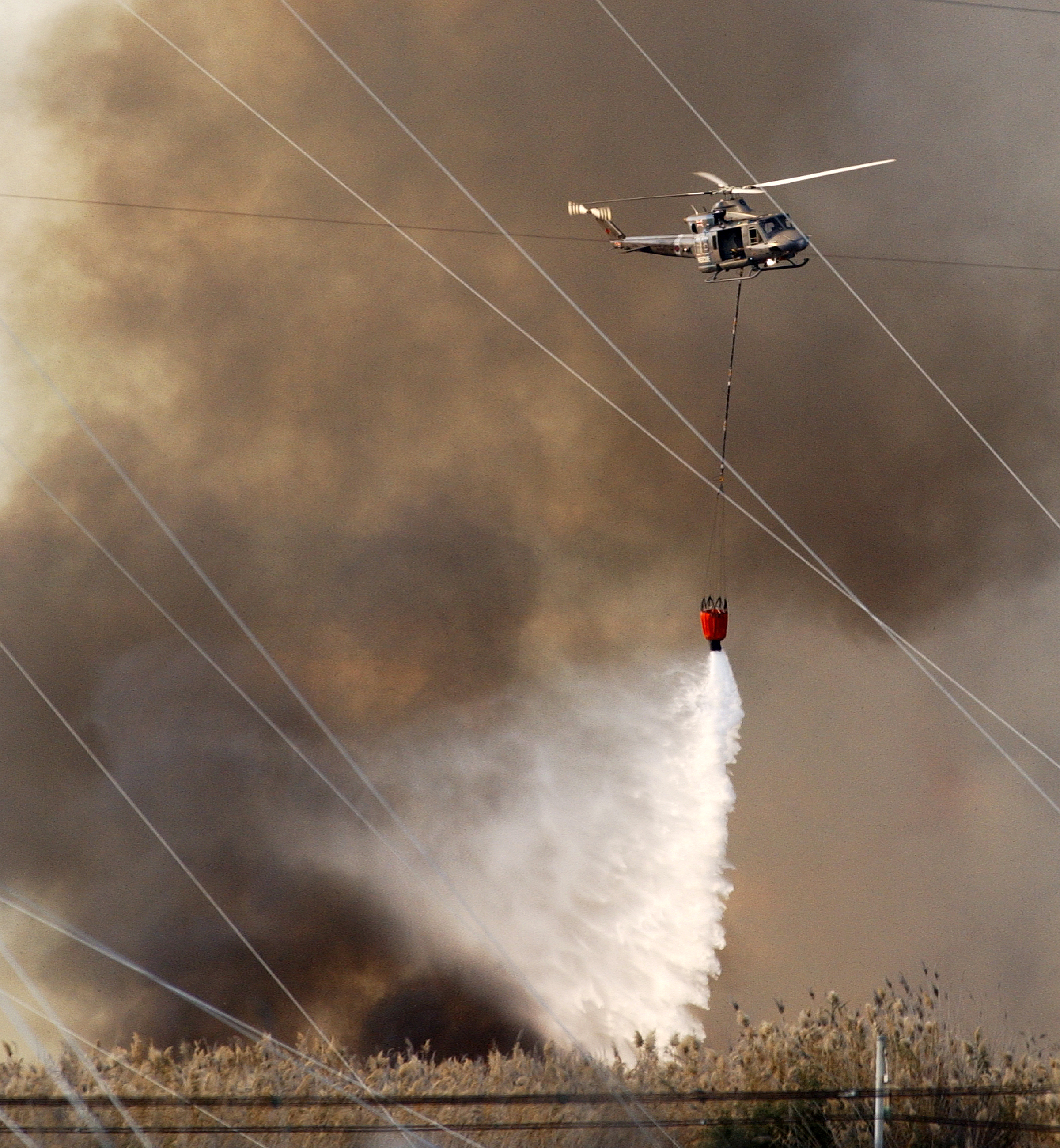 Helicopter drops water amid smokey wildfire.